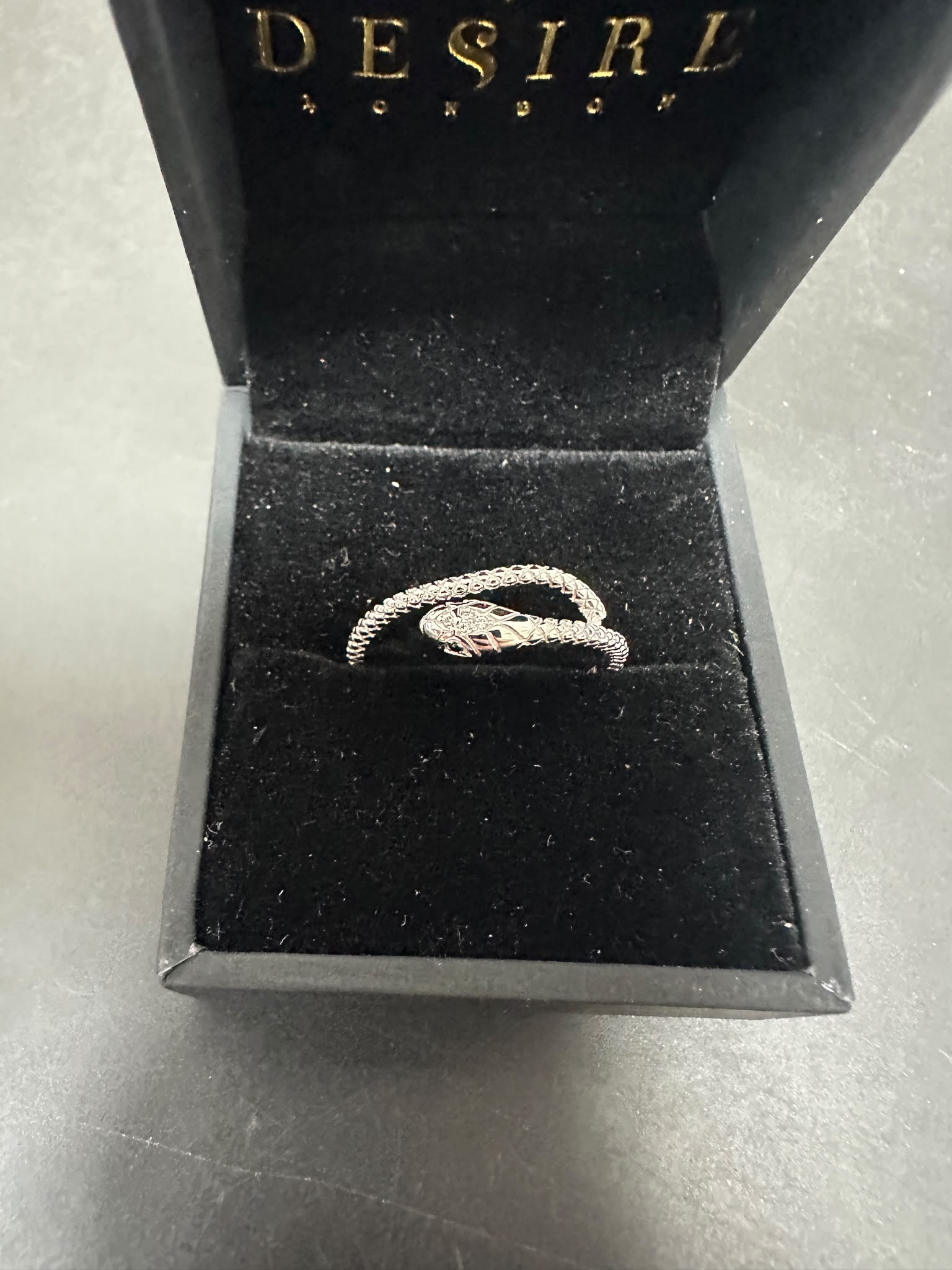 Sterling silver snake ring cz placed in a black velvet box with the Desire London logo.