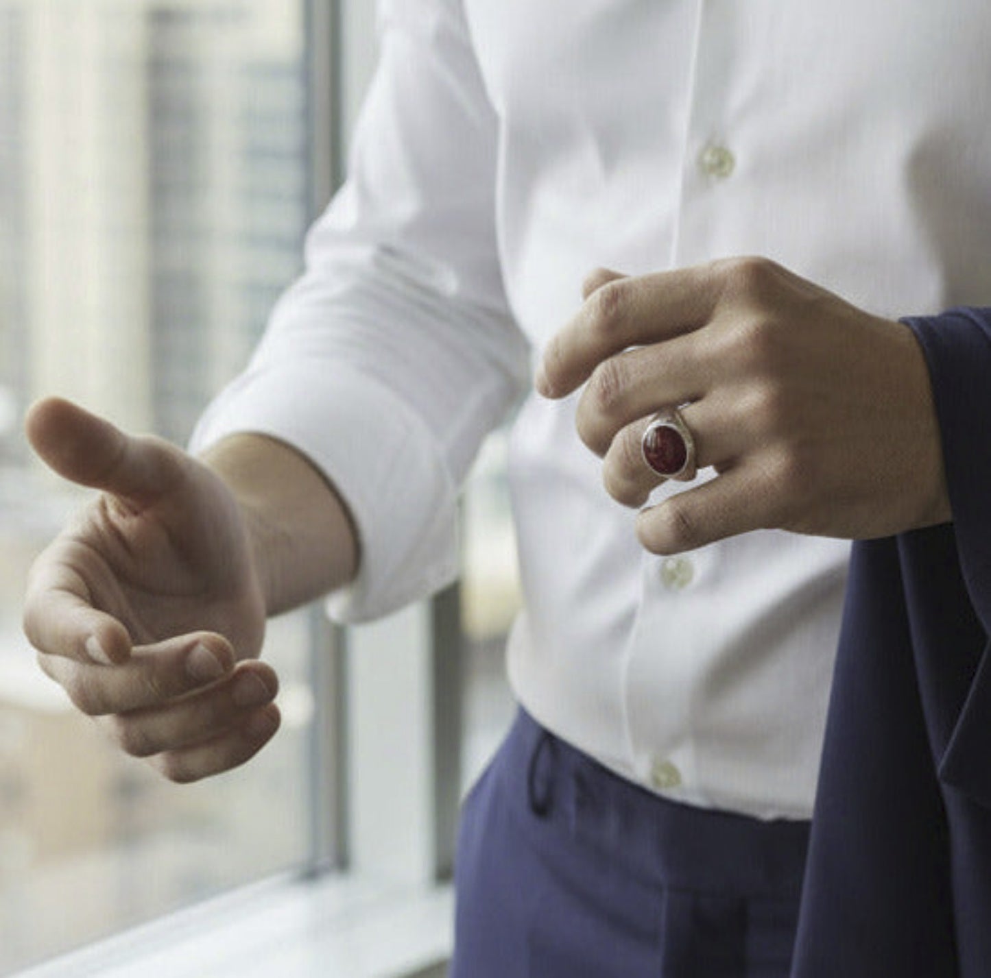 Silver ring with a red stone in a red box on a gray surface
